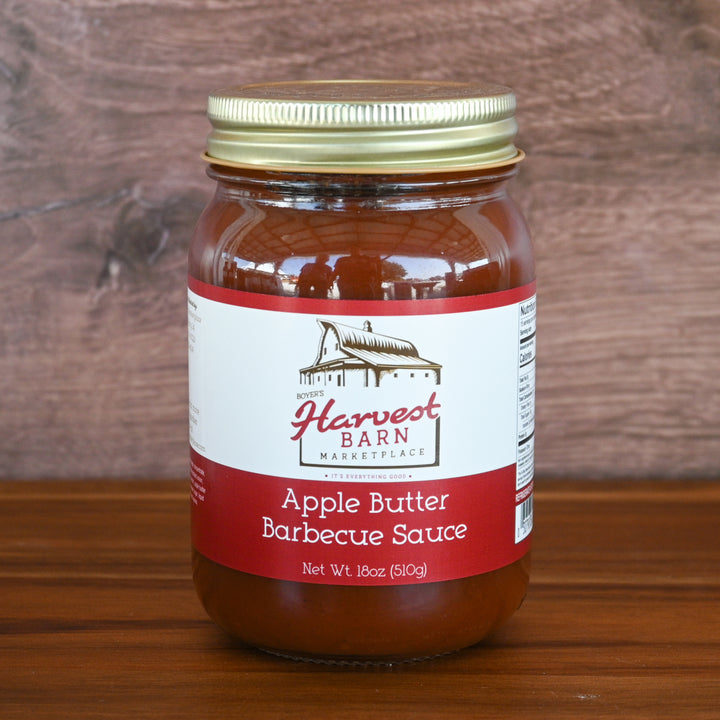 Jar of Apple Butter Barbecue Sauce from Harvest Barn Marketplace on a wooden surface with a wooden background.