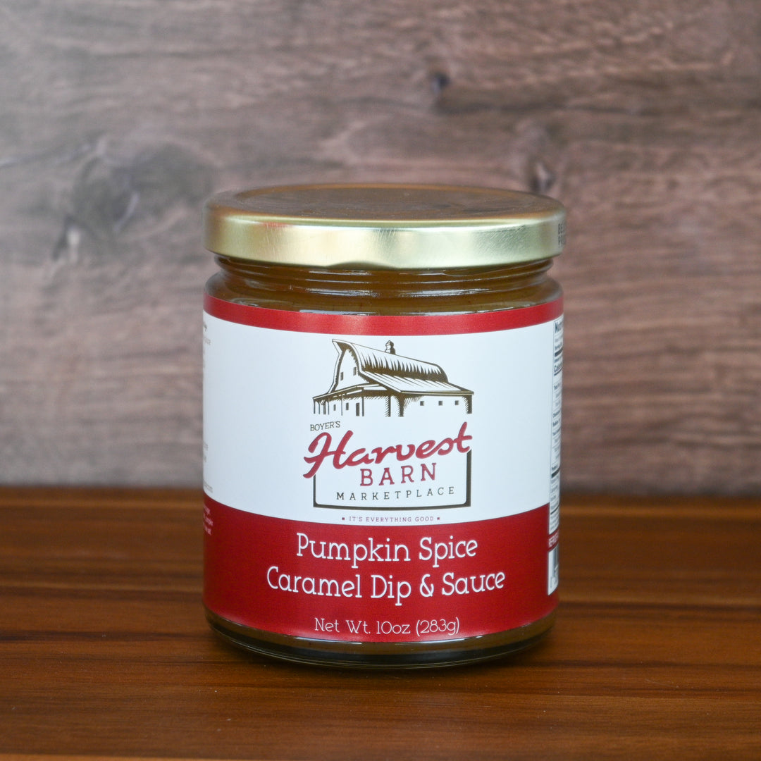Jar of Harvest Barn Pumpkin Spice Caramel Dip & Sauce on a wooden surface with a wooden background